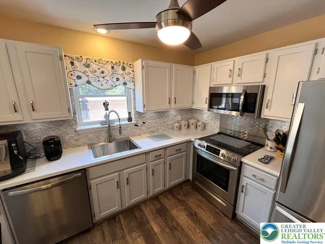 a kitchen with stainless steel appliances a sink cabinets and a window