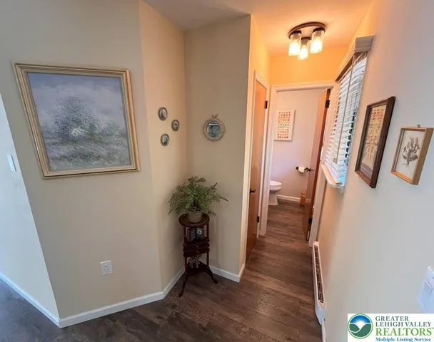 a view of a hallway with wooden floor and a bathroom