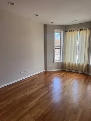 an empty room with wooden floor and windows with curtains view