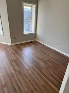 a view of an empty room with wooden floor and closet