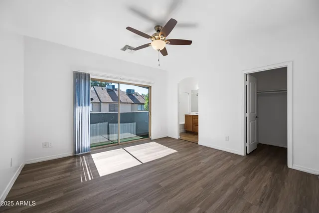 an empty room with wooden floor fan and windows