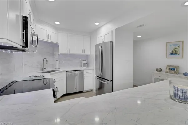 a kitchen with a refrigerator sink and white cabinets