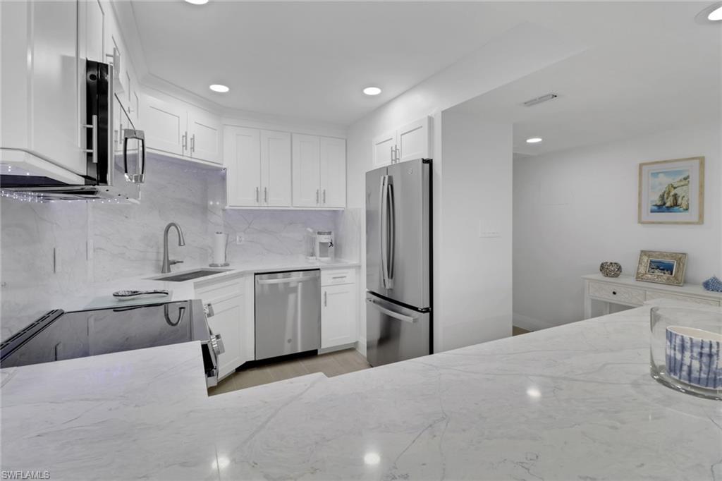 1 Bluebill Avenue, Unit 410 Naples, FL 34108 - Photo 11 of 36 a kitchen with a refrigerator sink and white cabinets