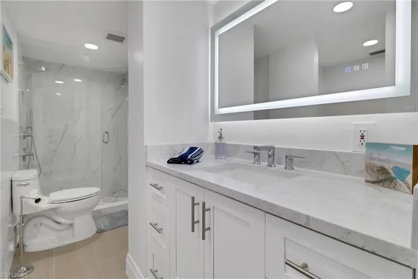 a bathroom with a granite countertop sink mirror vanity and toilet