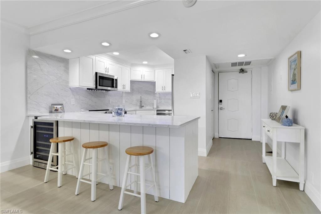 1 Bluebill Avenue, Unit 410 Naples, FL 34108 - Photo 7 of 36 a kitchen with kitchen island cabinets and chairs in it
