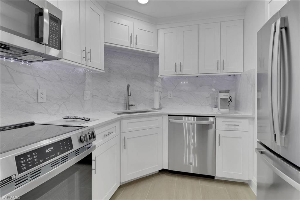 1 Bluebill Avenue, Unit 410 Naples, FL 34108 - Photo 9 of 36 a kitchen with white cabinets and appliances