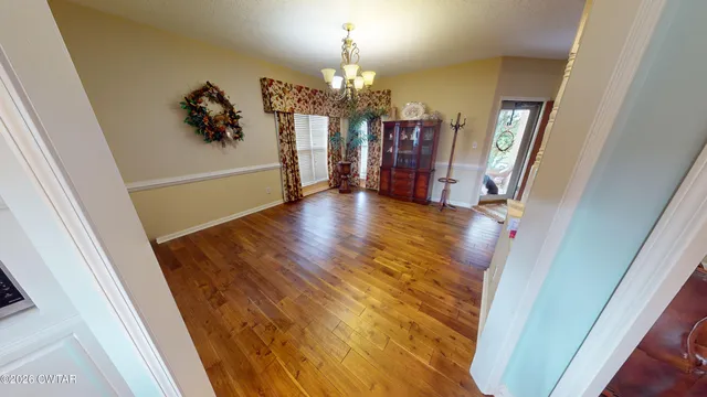 a view of a hallway to a livingroom with furniture wooden floor and a chandelier