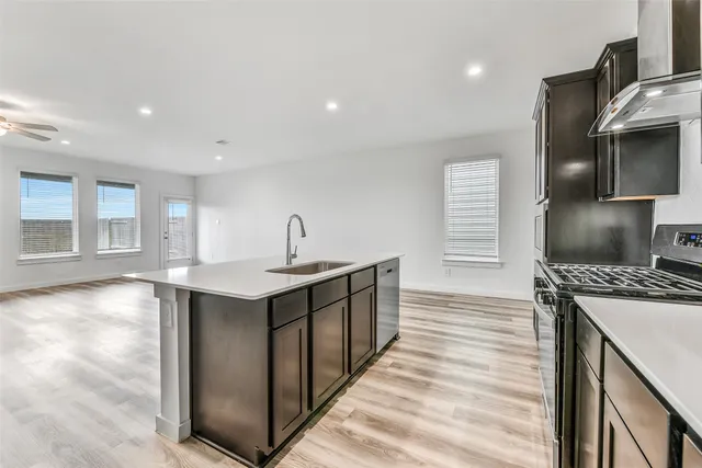 a kitchen with stainless steel appliances granite countertop a refrigerator a stove and a sink with wooden floor