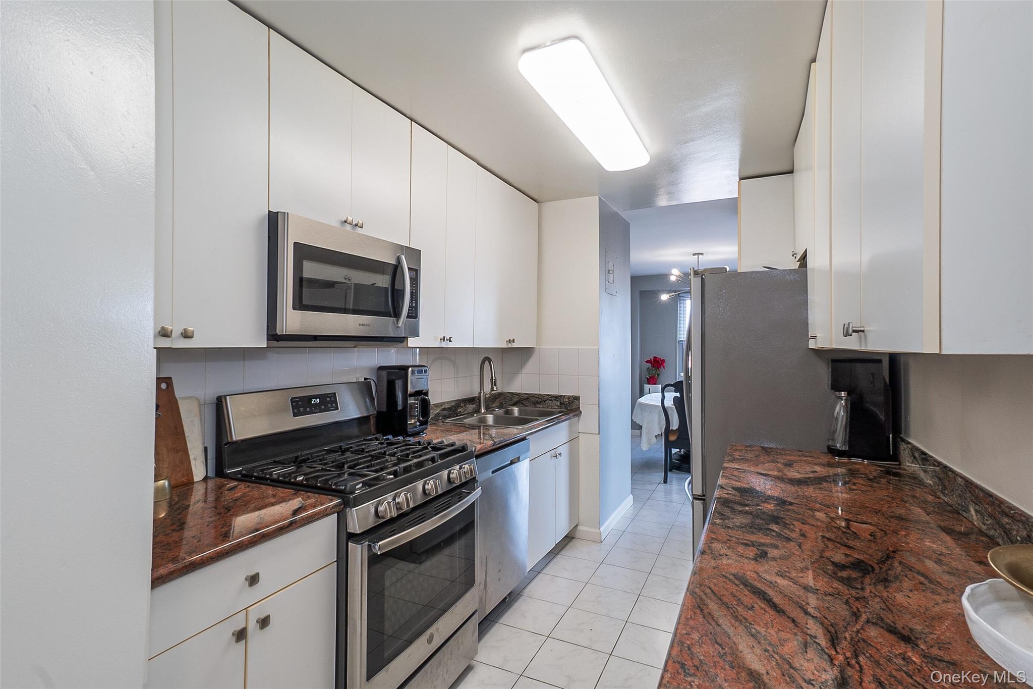85-15 Main Street, Unit J12 Queens, NY 11435 - Photo 12 of 26 a kitchen with stainless steel appliances granite countertop a stove a sink and a refrigerator