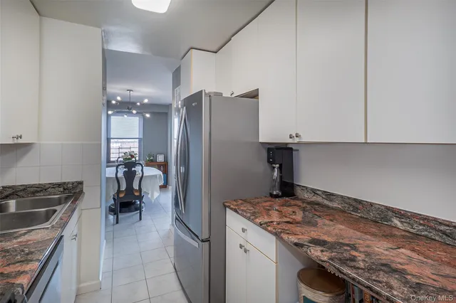 a view of a refrigerator in kitchen and an empty room