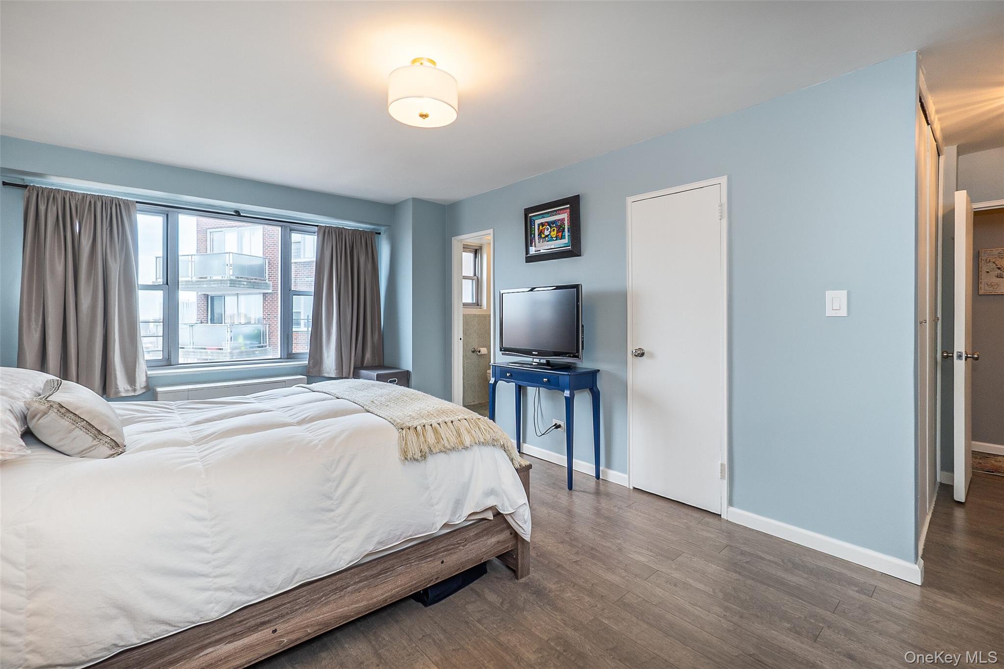 85-15 Main Street, Unit J12 Queens, NY 11435 - Photo 20 of 26 a bedroom with a bed and a flat tv screen on a dresser