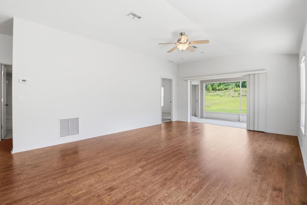 826 West Cockatiel Loop Hernando, FL 34442 - Photo 5 of 40 an empty room with wooden floor chandelier fan and windows