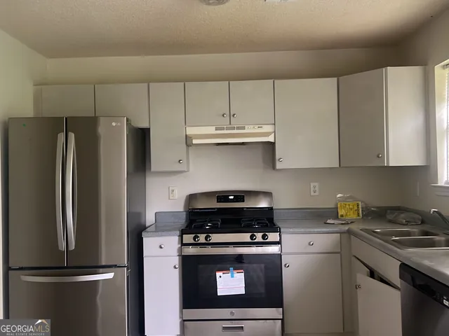 a kitchen with stainless steel appliances granite countertop a refrigerator stove and white cabinets
