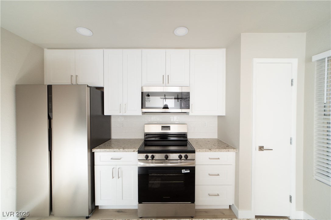 8101 West Flamingo Road, Unit 1057 Las Vegas, NV 89147 - Photo 1 of 38 Kitchen with appliances with stainless steel finishes, light stone countertops, recessed lighting, and white cabinetry