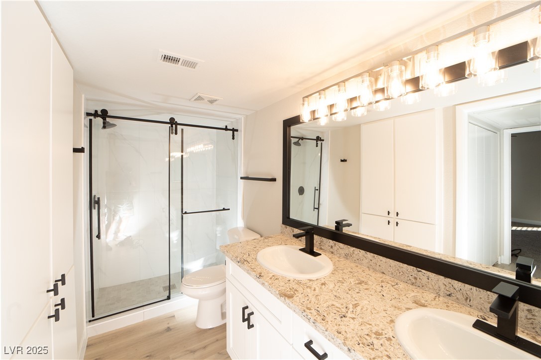 8101 West Flamingo Road, Unit 1057 Las Vegas, NV 89147 - Photo 12 of 38 Full bath with a marble finish shower, double vanity, and light wood-type flooring