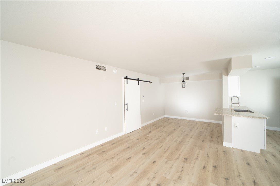 8101 West Flamingo Road, Unit 1057 Las Vegas, NV 89147 - Photo 10 of 38 Spare room featuring a barn door and light wood-type flooring