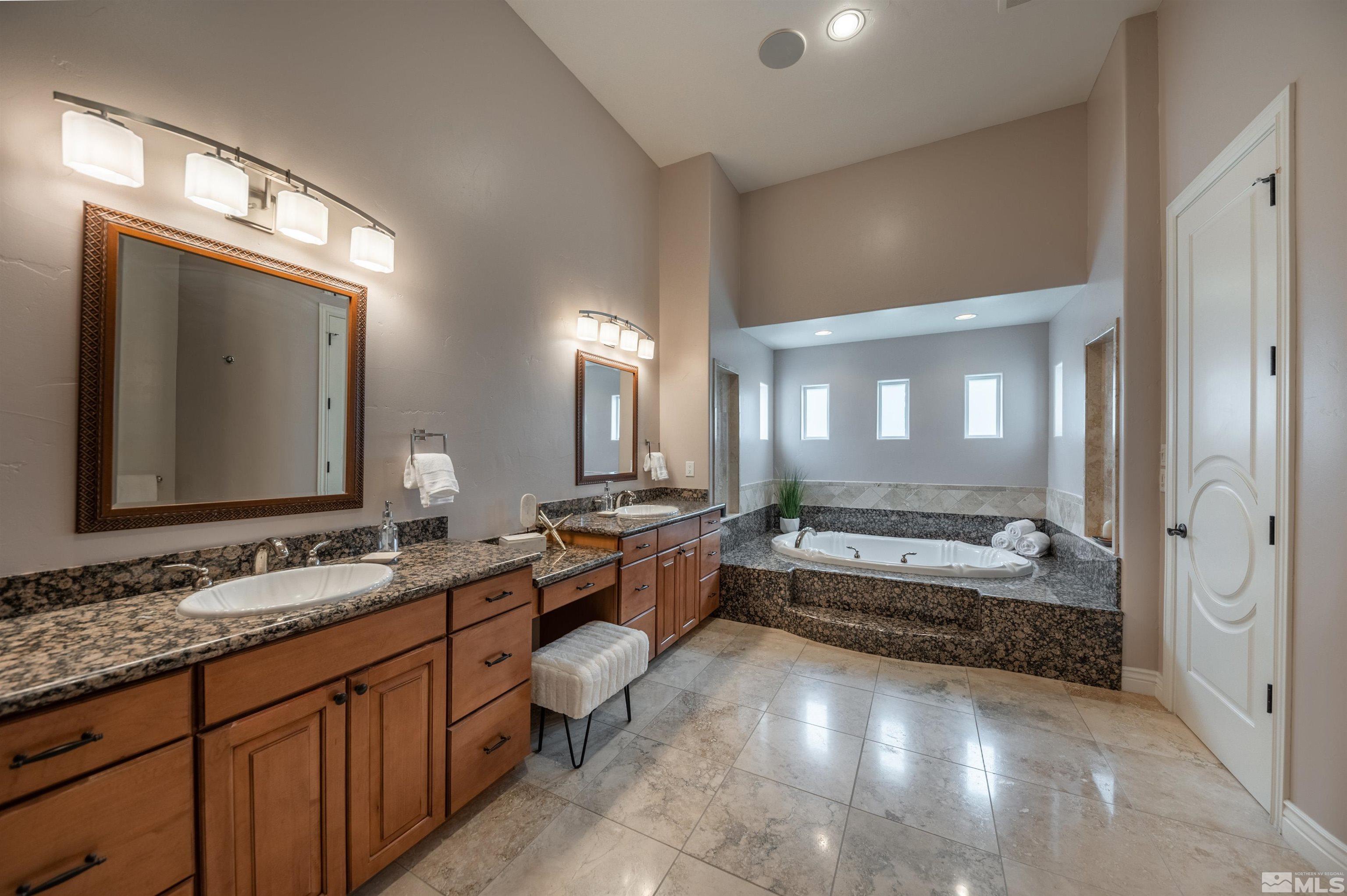 12880 Silver Wolf Road Reno, NV 89511 - Photo 12 of 35 a bathroom with double vanity sinks a large mirror and a bathtub
