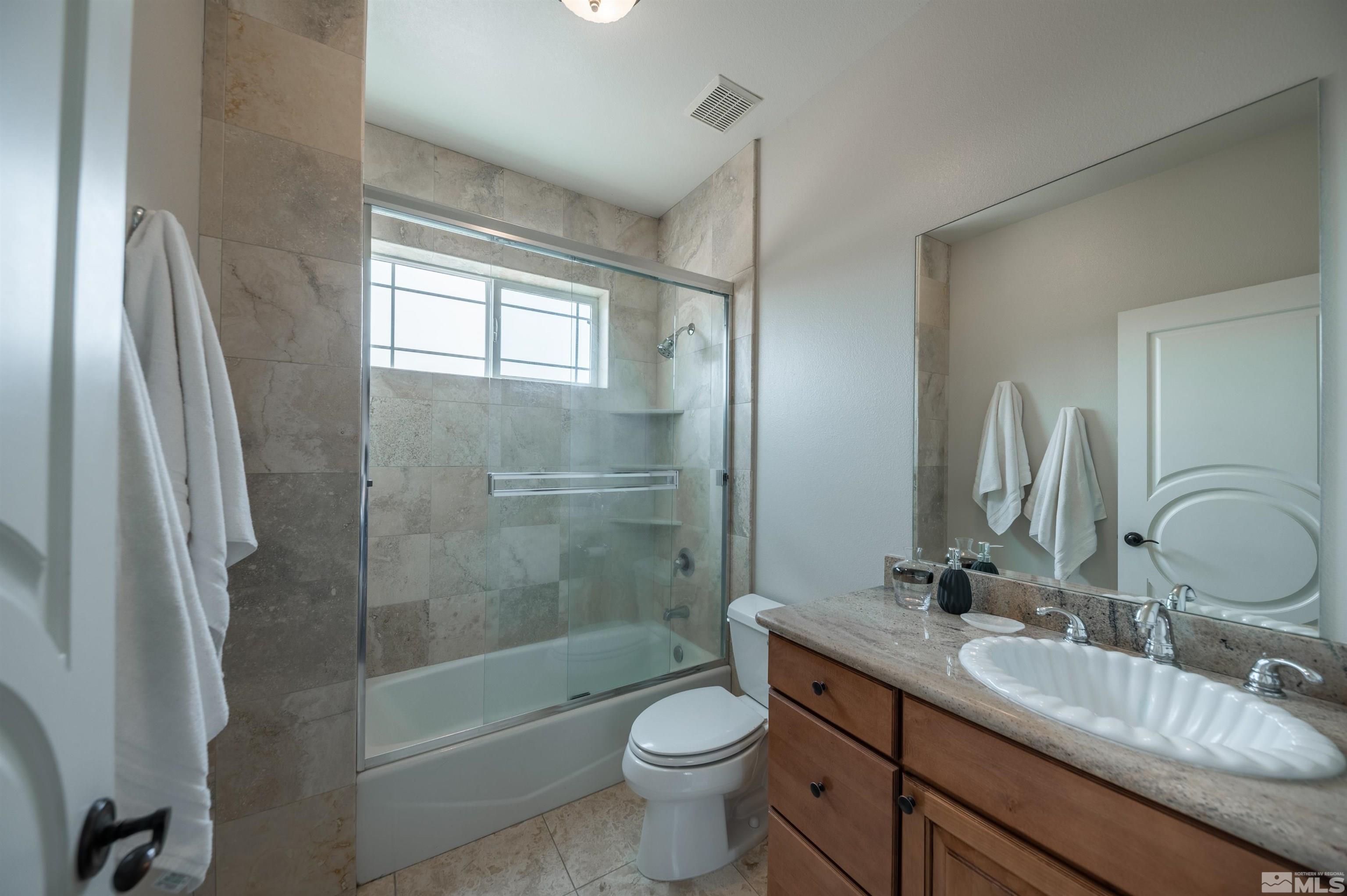 12880 Silver Wolf Road Reno, NV 89511 - Photo 16 of 35 a bathroom with a double vanity sink toilet mirror and shower