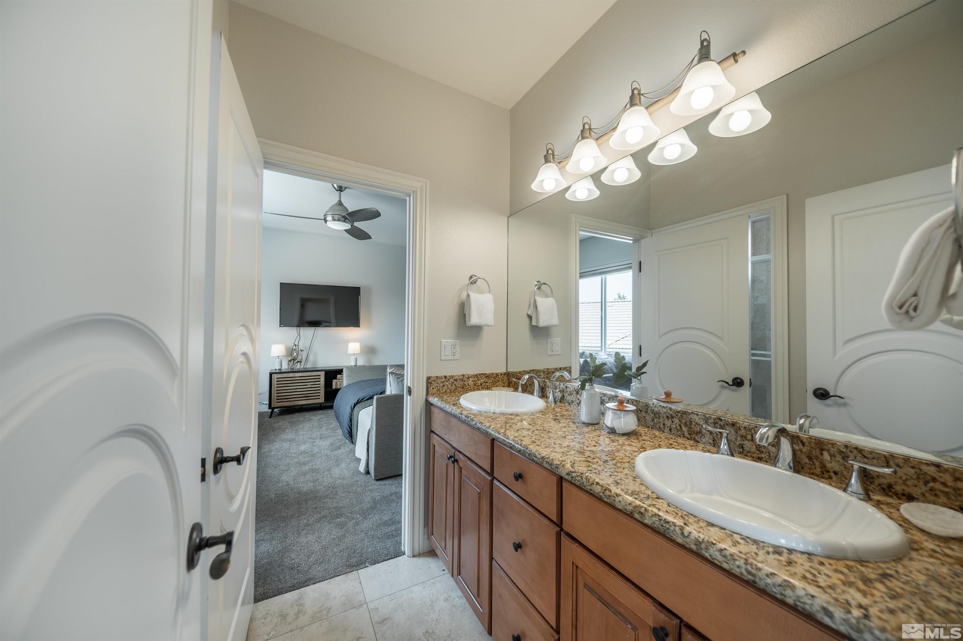 12880 Silver Wolf Road Reno, NV 89511 - Photo 18 of 35 a en suite bathroom with a granite countertop sink a light fixture and a mirror