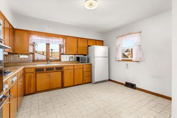 a kitchen with granite countertop a refrigerator a sink a stove and white cabinets