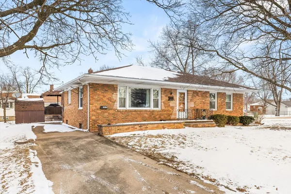 a front view of a house with a yard covered with snow