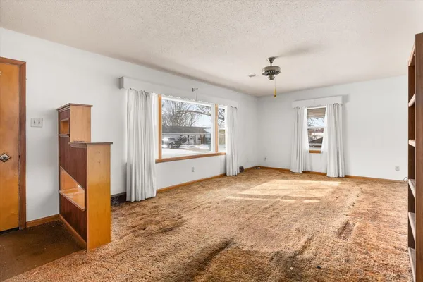 a view of empty room with window and refrigerator