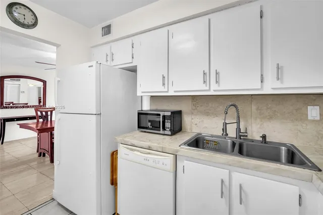 a kitchen with stainless steel appliances granite countertop a refrigerator sink and white cabinets