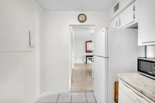 a kitchen with a refrigerator and white cabinets