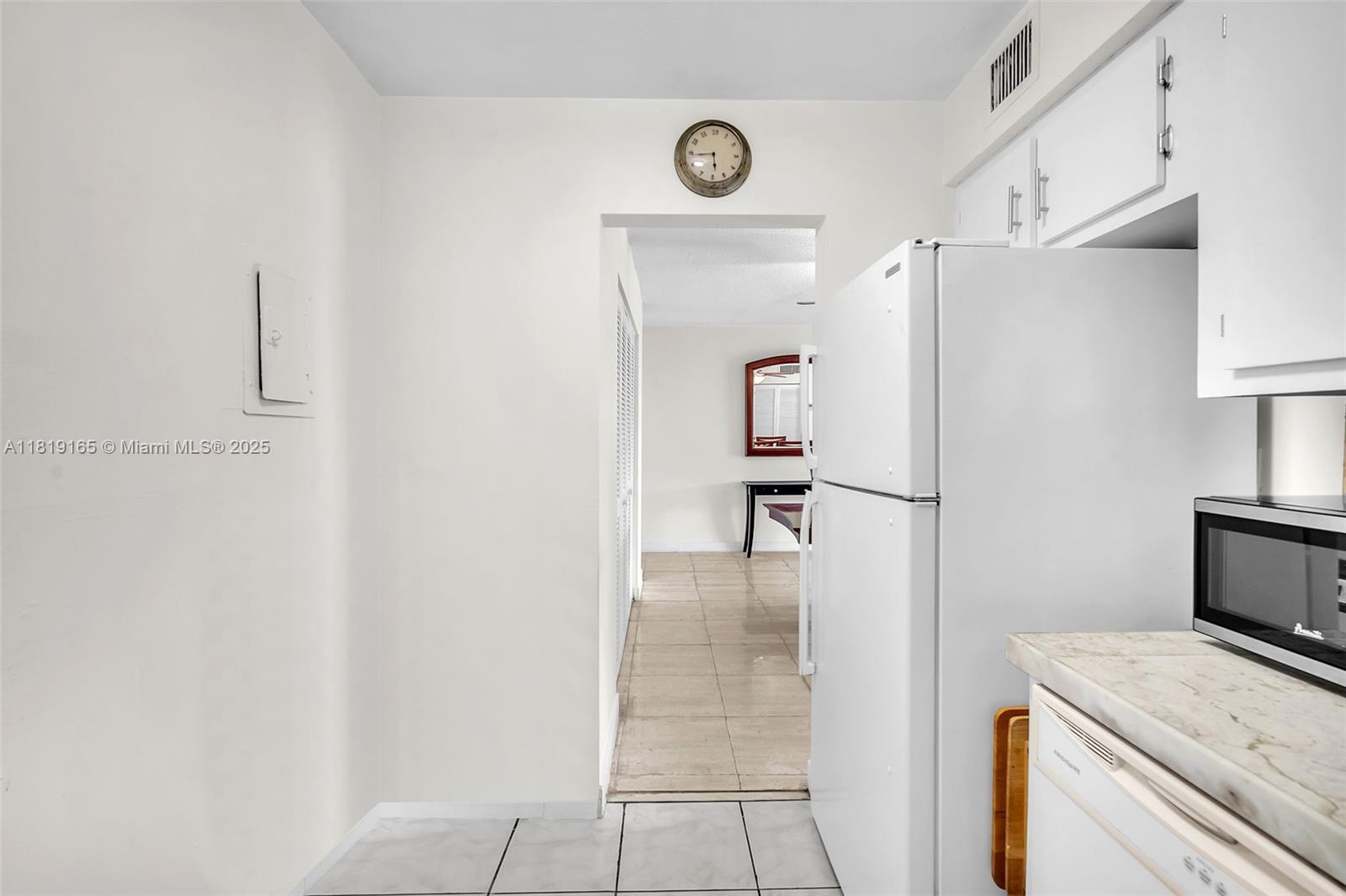 17800 Atlantic Boulevard, Unit 303 Sunny Isles Beach, FL 33160 - Photo 13 of 26 a kitchen with a refrigerator and white cabinets