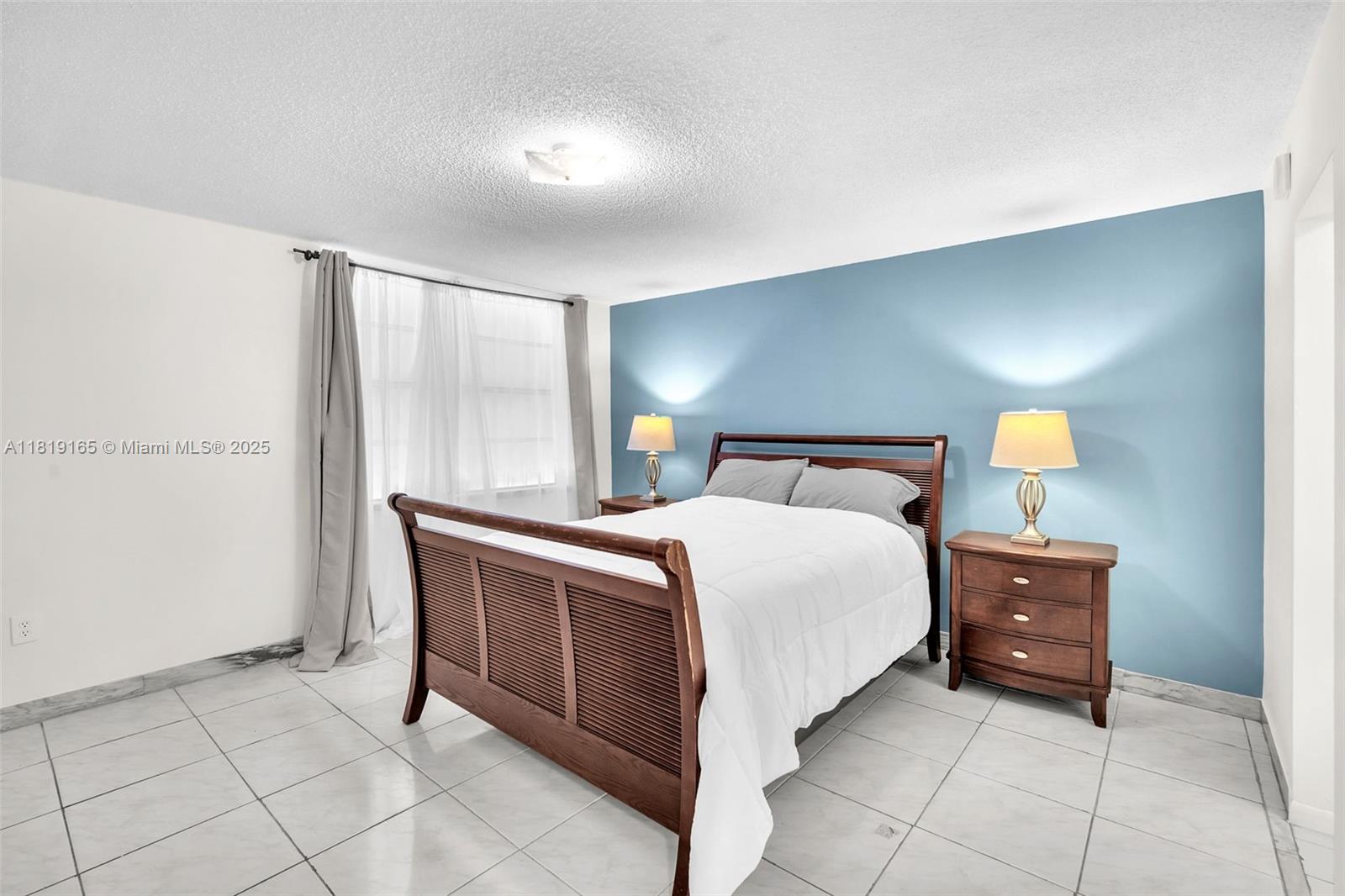 17800 Atlantic Boulevard, Unit 303 Sunny Isles Beach, FL 33160 - Photo 14 of 26 a bedroom with a bed and a lamp