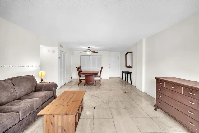 a living room with furniture and a dining table with bookshelf