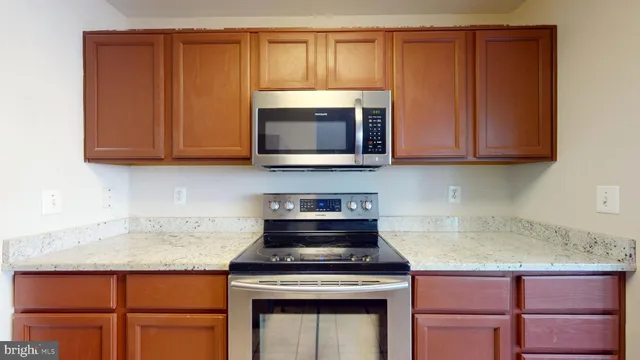 a kitchen with granite countertop wood cabinets and stainless steel appliances