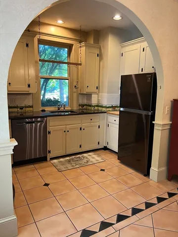 a kitchen with granite countertop a refrigerator a stove top oven and a sink