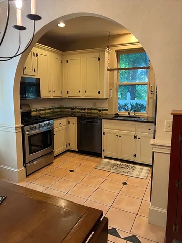 a kitchen with stainless steel appliances granite countertop a stove a sink and a microwave