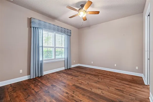 a view of a big room with wooden floor and a ceiling fan
