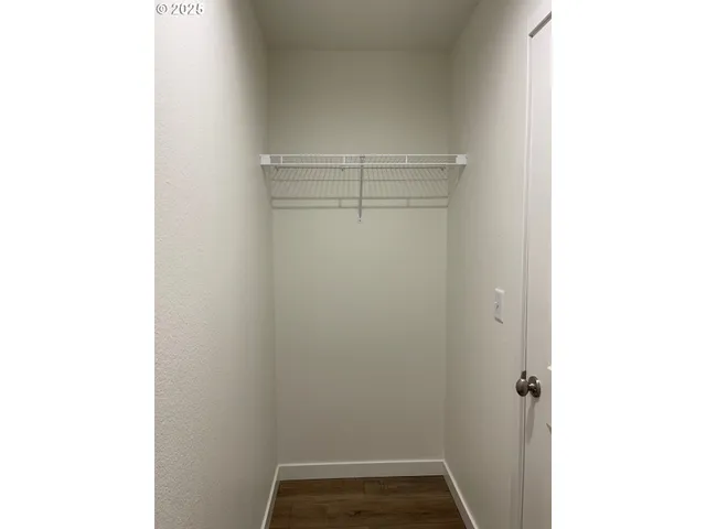 a view of an empty room with wooden floor and closet