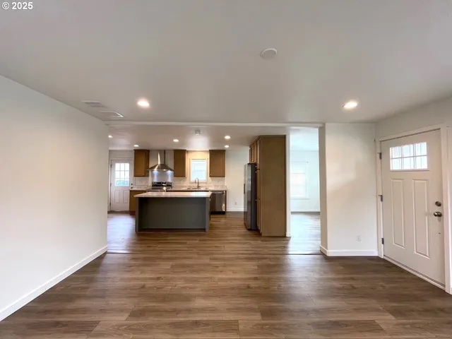 a living room with stainless steel appliances kitchen island granite countertop a refrigerator and a stove top oven