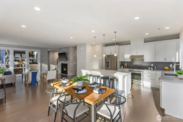a kitchen with stainless steel appliances kitchen island granite countertop a dining table chairs and white cabinets
