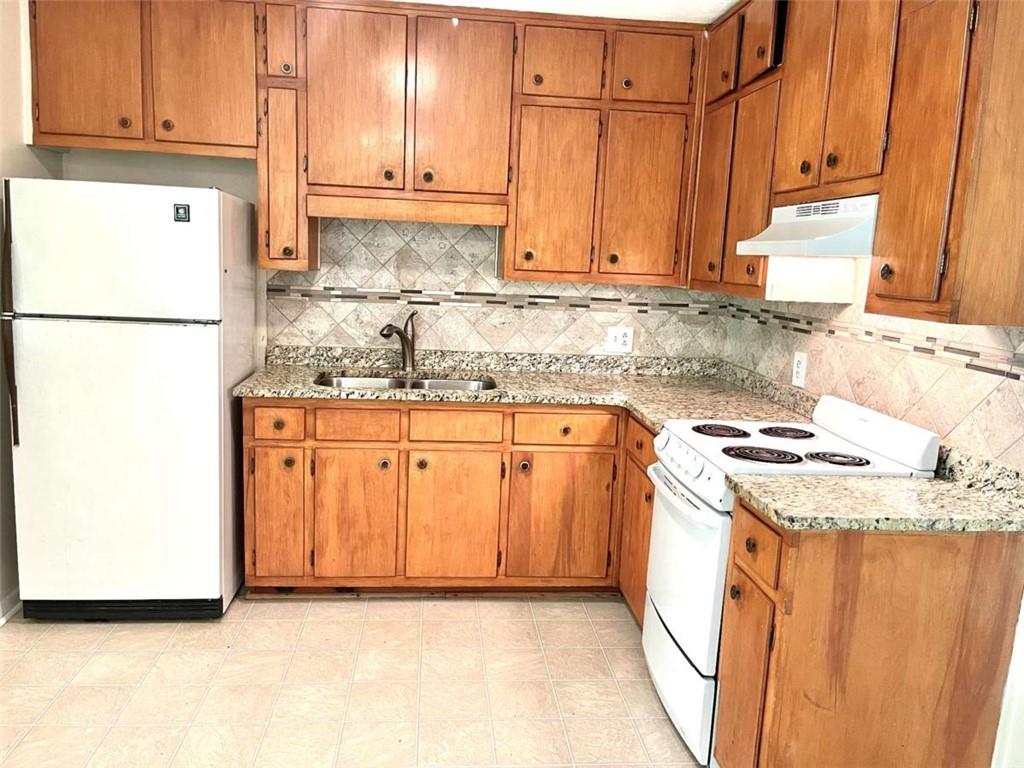 1002 Level Creek Road, Unit 201 Sugar Hill, GA 30518 - Photo 6 of 13 a kitchen with granite countertop a sink a stove and a refrigerator