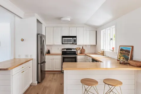 a kitchen with a refrigerator a stove a sink dishwasher and wooden cabinets with wooden floor