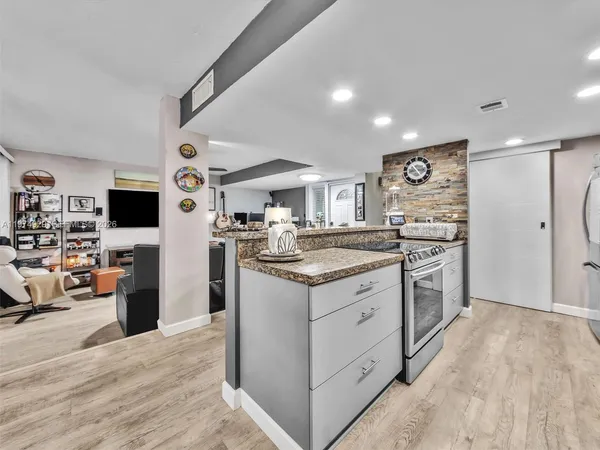 a large kitchen with stainless steel appliances a large counter top a stove a chimney a sink and a refrigerator
