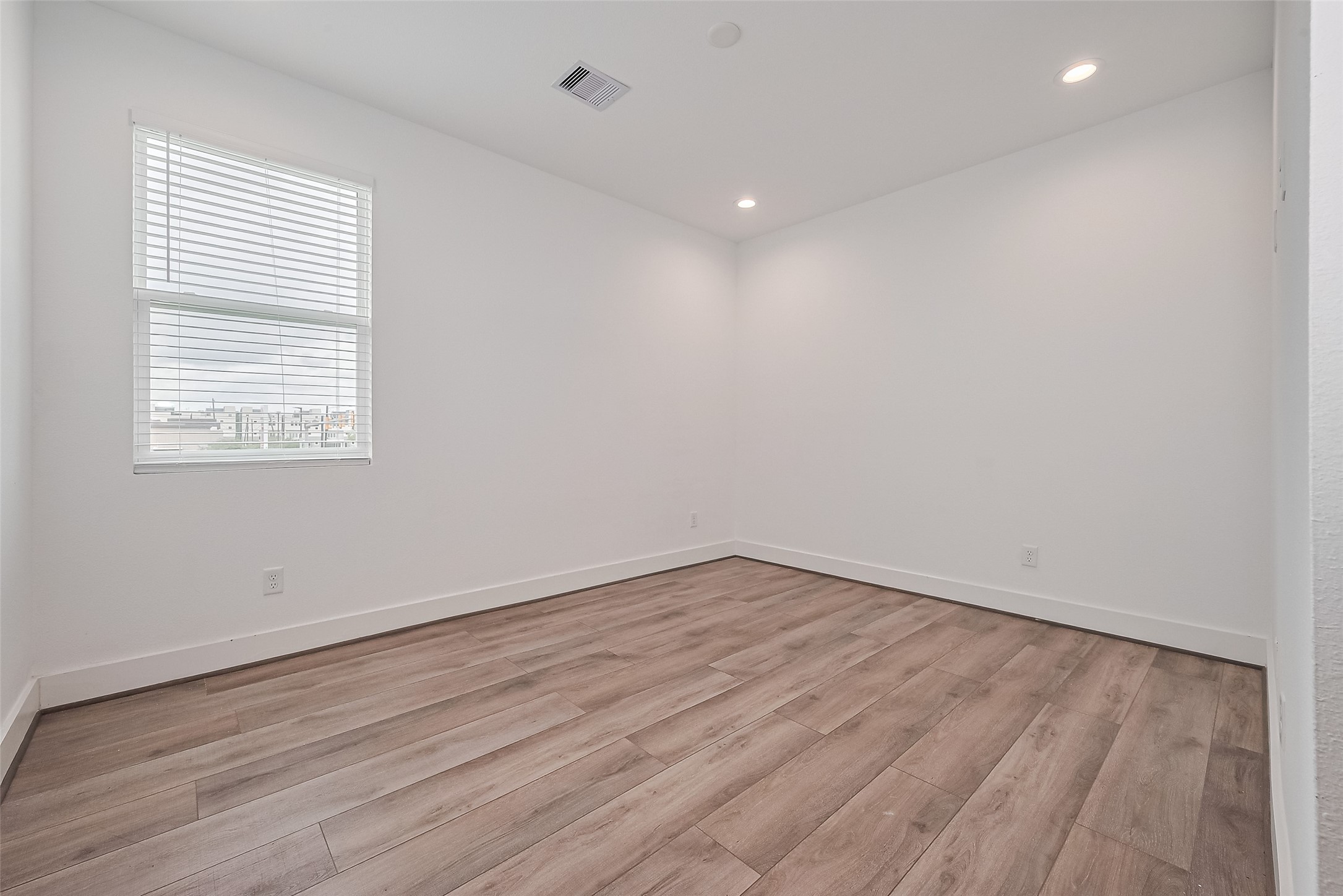 3510 Hadley Street Houston, TX 77004 - Photo 26 of 48 A sunlit retreat, this bedroom features wood floors, recessed lighting, and a private bath—offering both comfort and privacy.