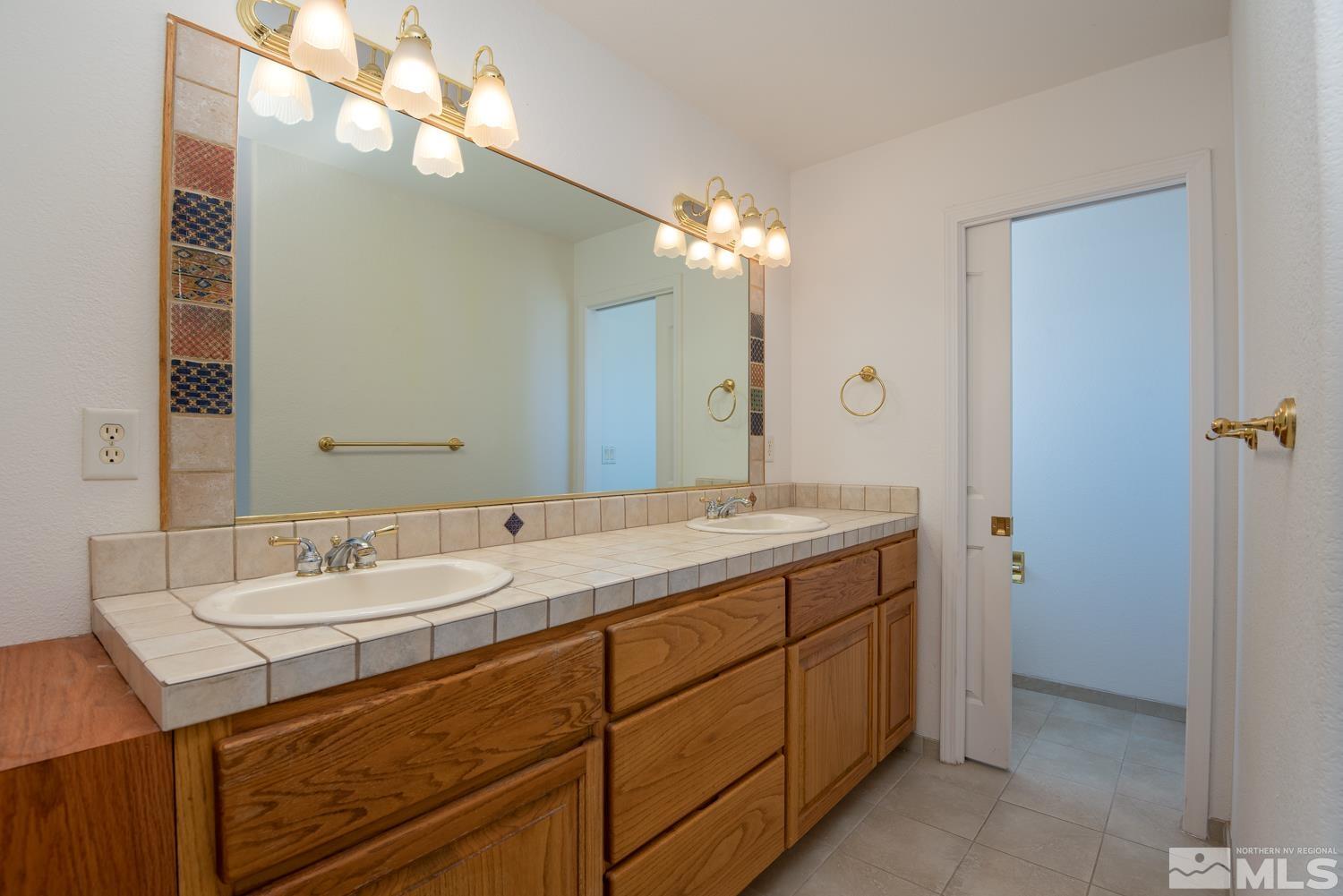 2876 Jackie Circle Minden, NV 89423 - Photo 17 of 40 a bathroom with a granite countertop sink a large mirror and a shower