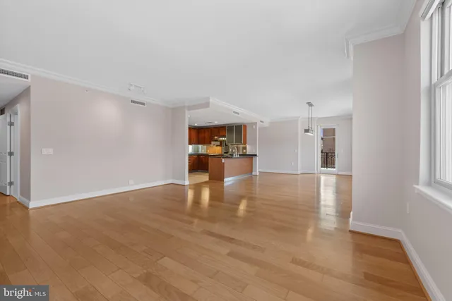 a view of an empty room with window and wooden floor