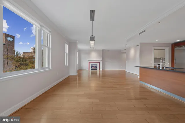 an empty room with wooden floor chandelier and windows