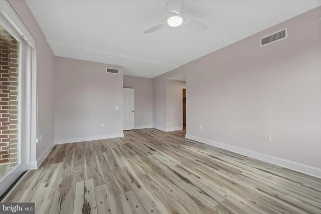 a view of an empty room with wooden floor and a window