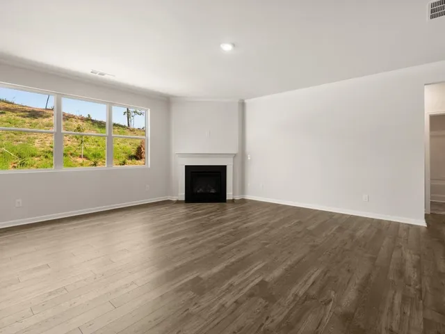 an empty room with wooden floor and a fireplace
