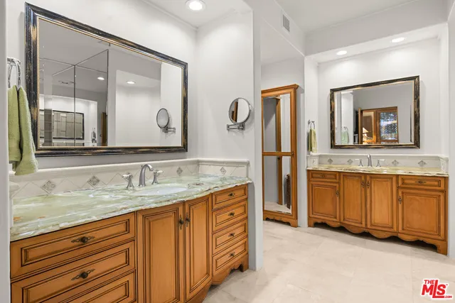 a bathroom with a granite countertop double vanity sink and mirror