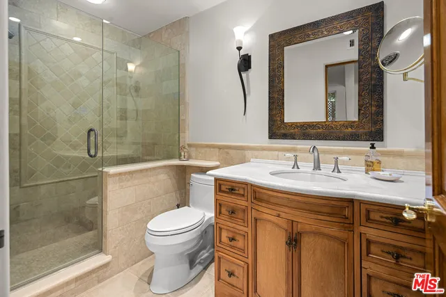 a bathroom with a granite countertop sink a toilet a mirror and shower