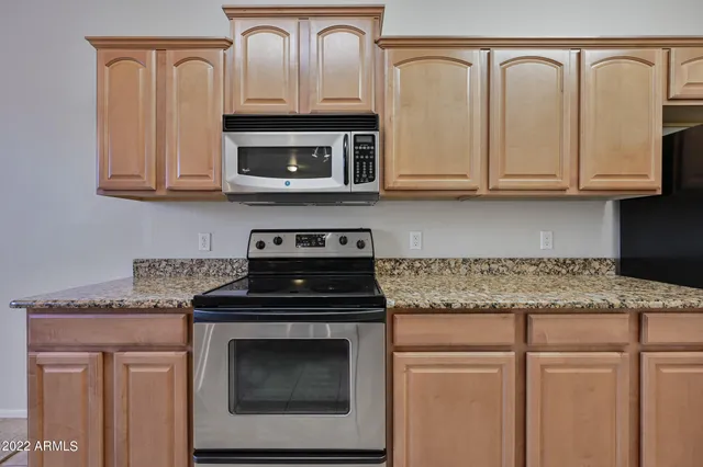 a kitchen with granite countertop white cabinets and a stove top oven
